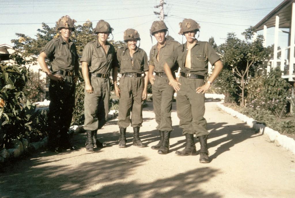 Members of 8 platoon, C Company, 6th Battalion, Royal Australian Regiment (6RAR), in the battalion lines at Enoggera, Queensland, prior to deployment to Vietnam in May 1966. From left: 2781803 Private (Pte) Rodney Cox of Ganmain, NSW; 2781794 Pte Gordon Stafford of Gunnedah, NSW; 2781823 Pte Neil (Pop) Baker of Newcastle, NSW; 2781790 Pte Mark (Scrub) Minell of Moree, NSW; 2781809 Pte Graham Irvine of Coolamon, NSW. All five men were called up in the first intake of national service in July 1965. Note the protective steel helmets with camouflage netting, usually worn by Australian infantry on operations in areas known to have been mined by the enemy.